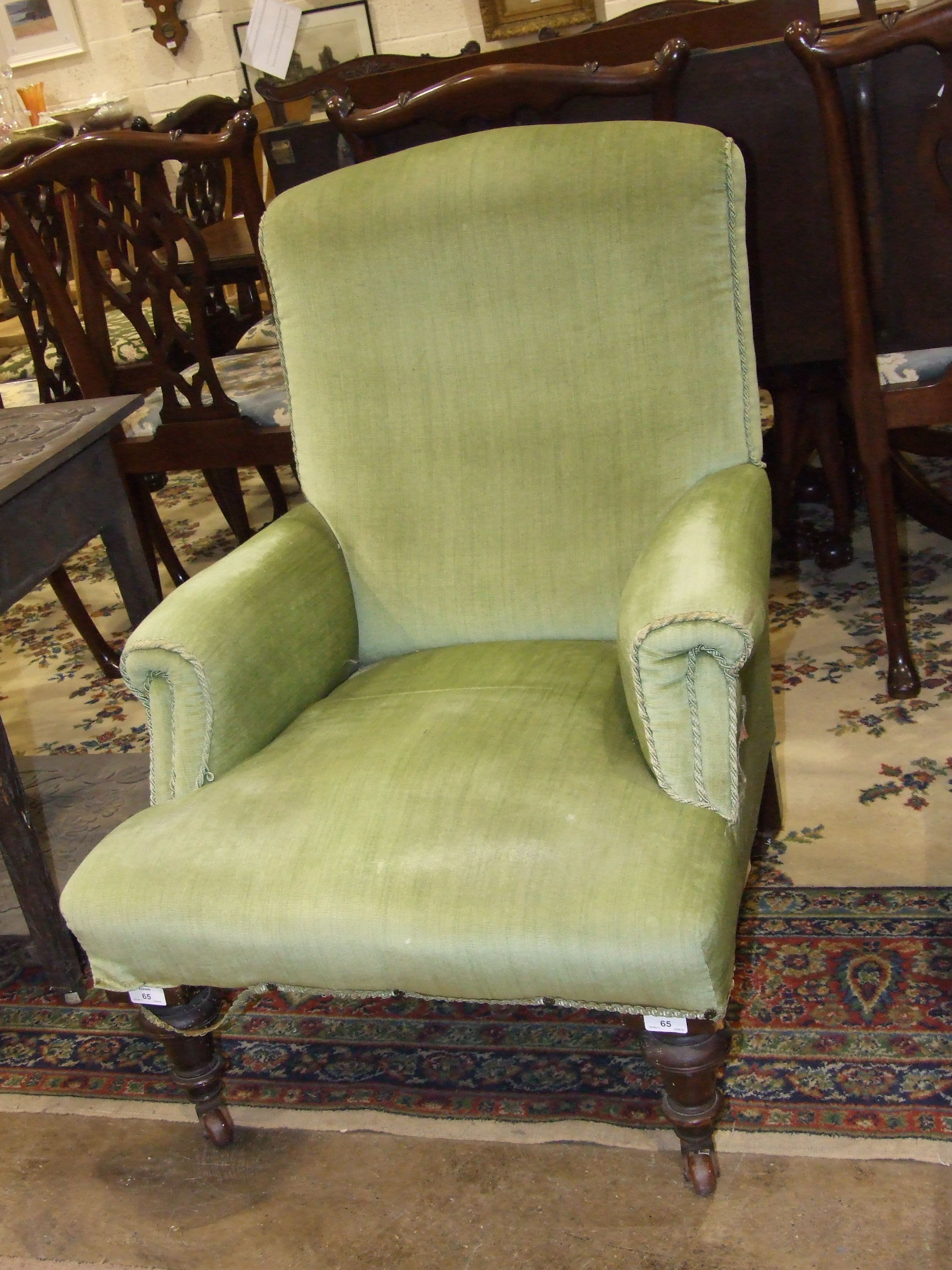 A late Victorian/early 20th century upholstered armchair on turned wood front legs, (af).