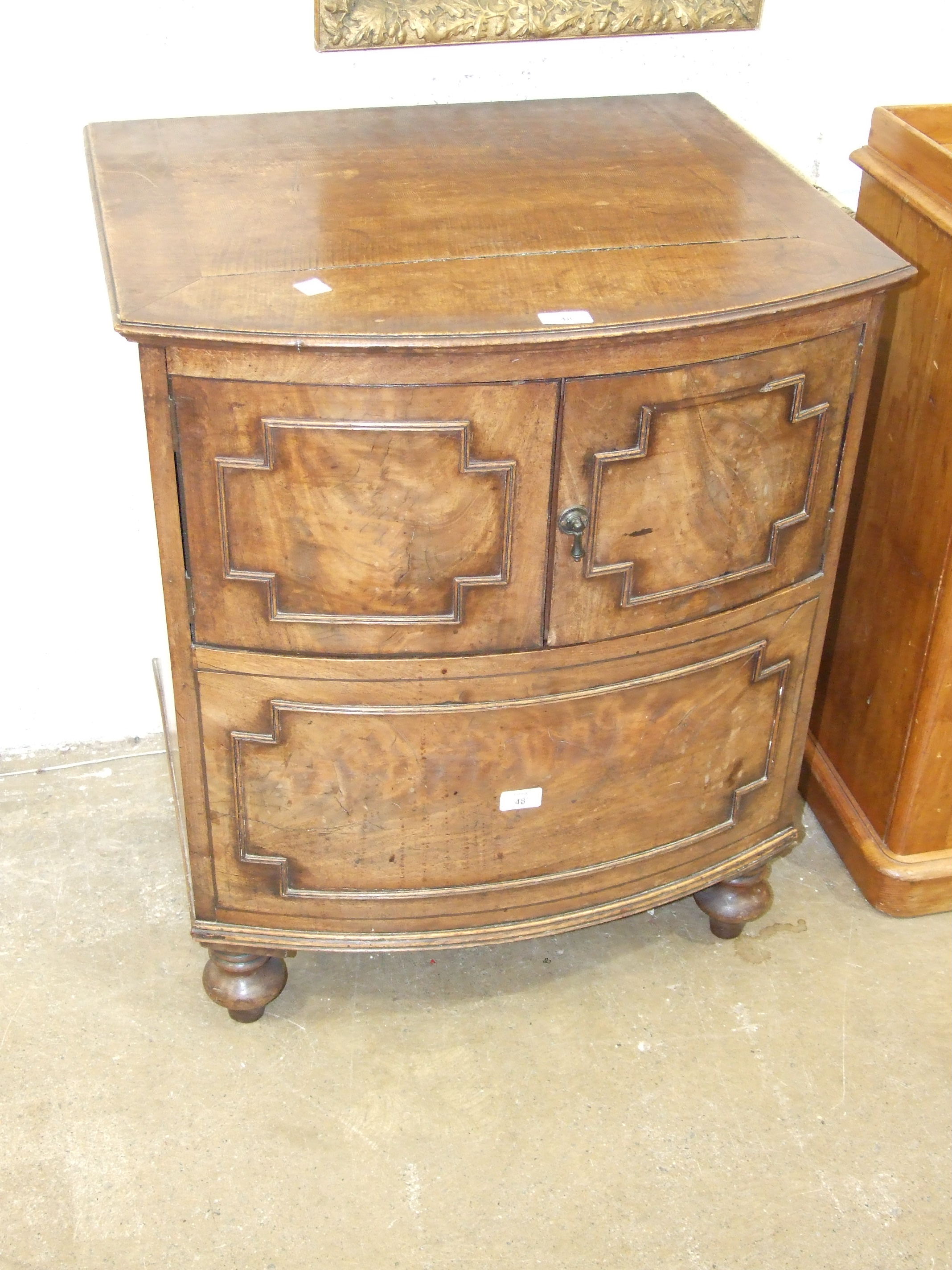 A Georgian converted bow-fronted commode having a pair of cupboard doors, on turned legs, 65cm wide,