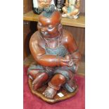 A lacquered wood Oriental figure of a male seated holding a stone, on base, 41cm high overall.