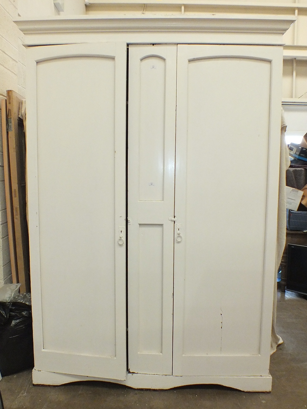 A large painted pine wardrobe/housekeeper's cupboard, the cornice above a pair of doors, on plinth