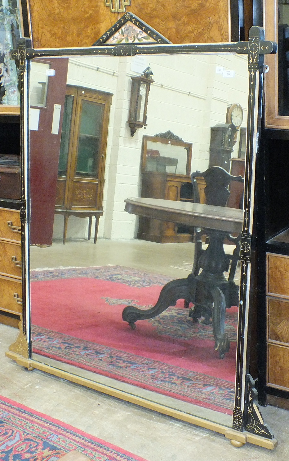 An ebonised wooden-framed over-mantel mirror with gilt decoration, 129cm wide, 143.5cm high.