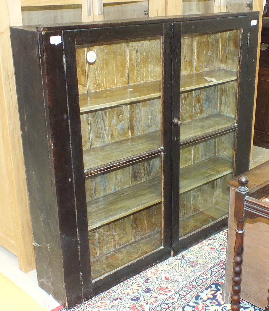 A stained wood bookcase fitted with a pair of glazed doors, 113cm wide, 108cm high.