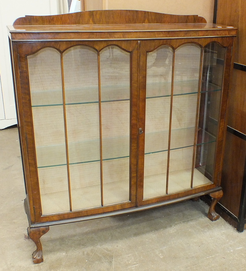 A walnut display cabinet, the rectangular top above a pair of glazed doors, on short cabriole legs