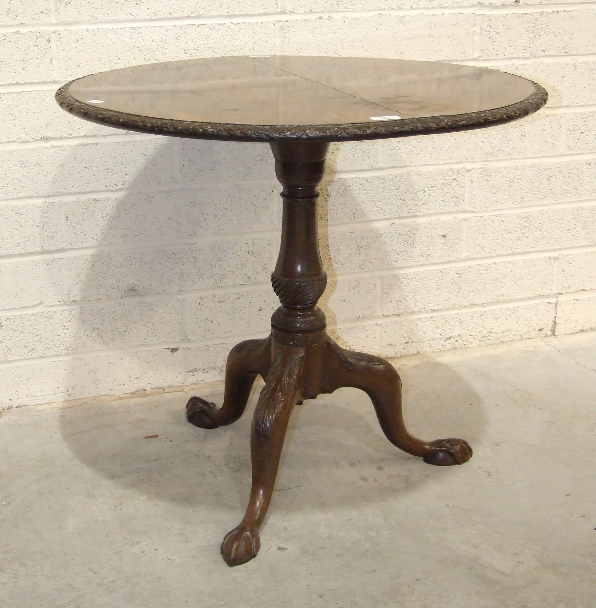 An 18th century mahogany tripod table stem, with leaf-carved legs, claw feet and later circular top,