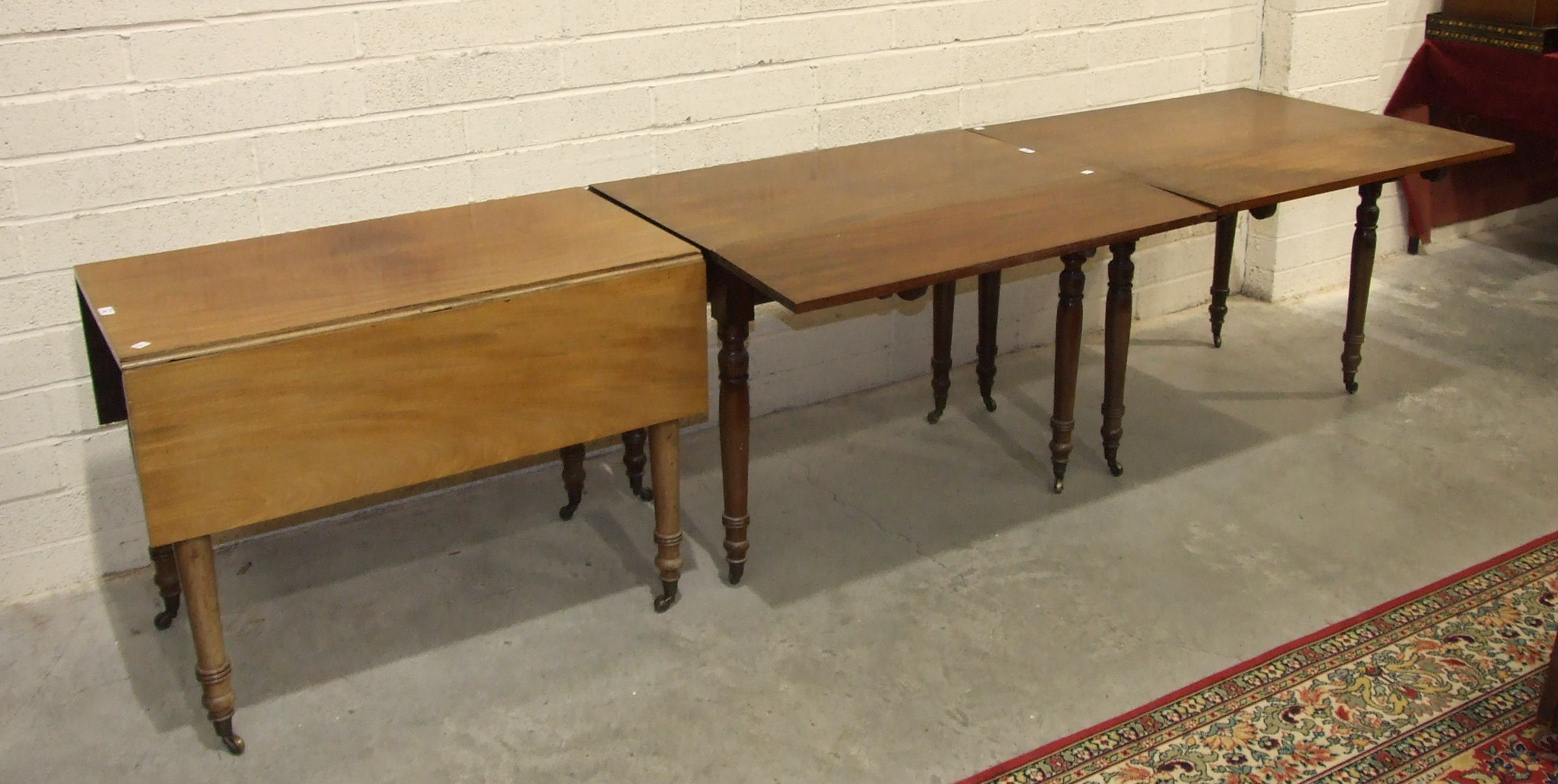 Three 19th century mahogany drop-leaf tables on turned legs, forming a dining table, each section