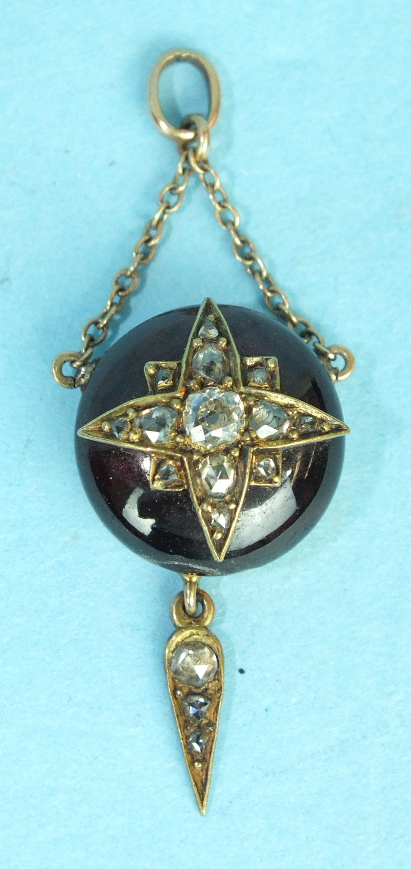 A Victorian cabochon garnet and diamond pendant, the round cabochon garnet overlaid with old-cut