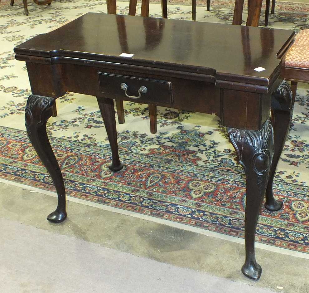 A mahogany fold-over card table in the George II style, the top with recess counter dishes above a