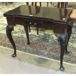 A mahogany fold-over card table in the George II style, the top with recess counter dishes above a