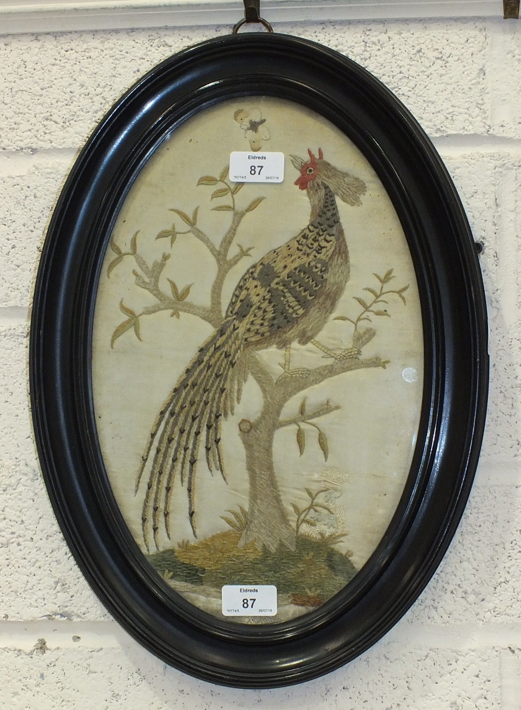 A 19th century oval embroidered silk picture of a pheasant perched in a tree, 38 x 23cm, (old