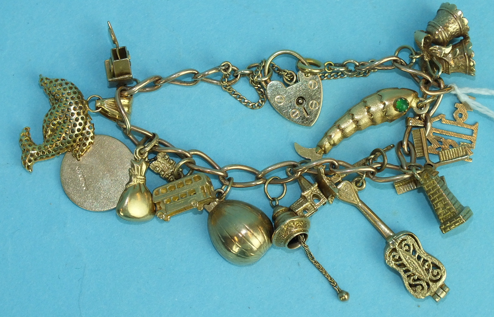 A 9ct gold curb-link bracelet with padlock clasp and fourteen charms, total weight 34.6g.