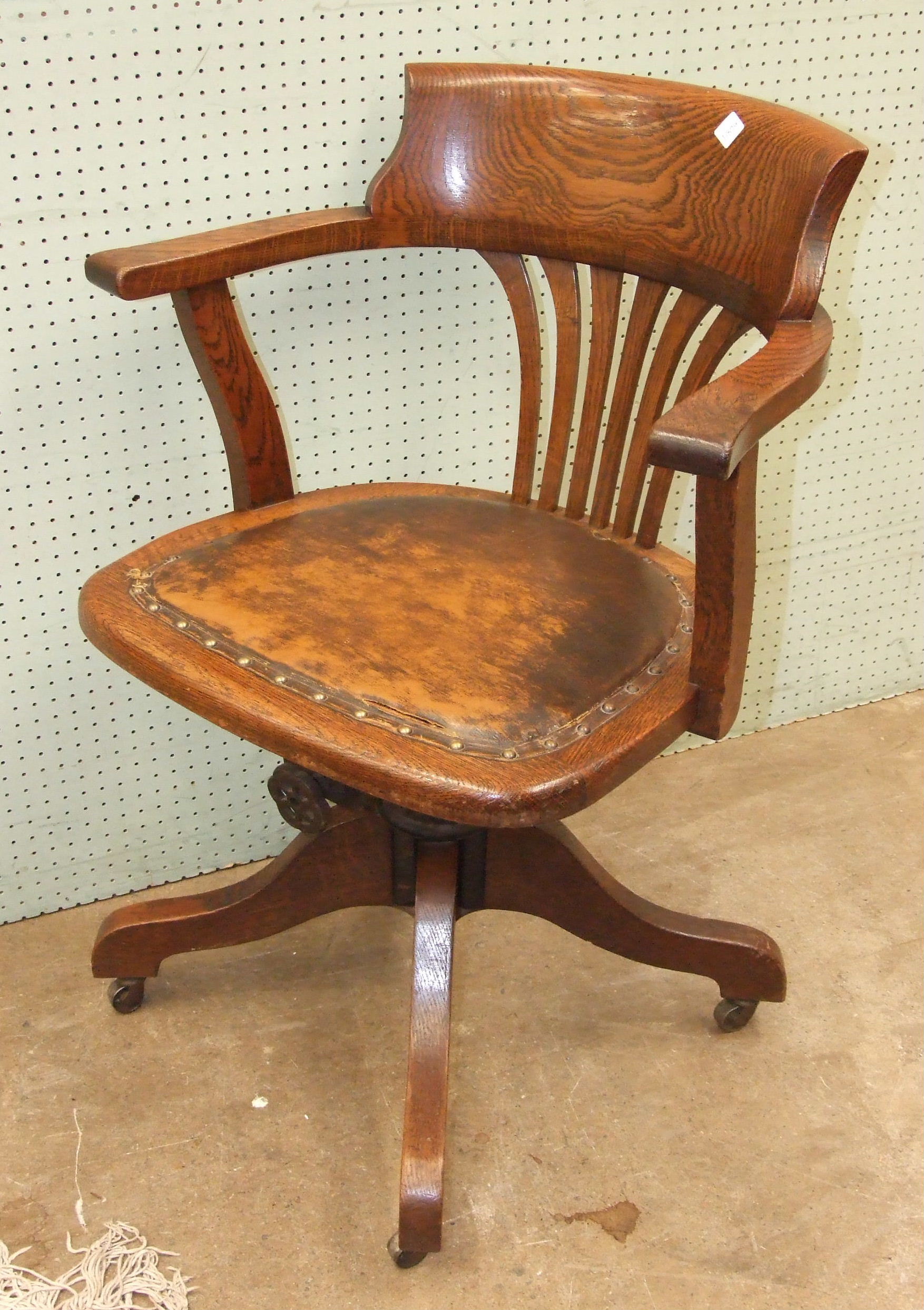 An oak swivel office armchair with padded seat, 84.5 cm high, 61cm wide.