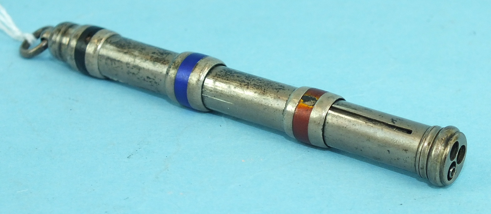 A white metal triple propelling pencil with black, blue and red enamel bands, stamped 'Sterling',