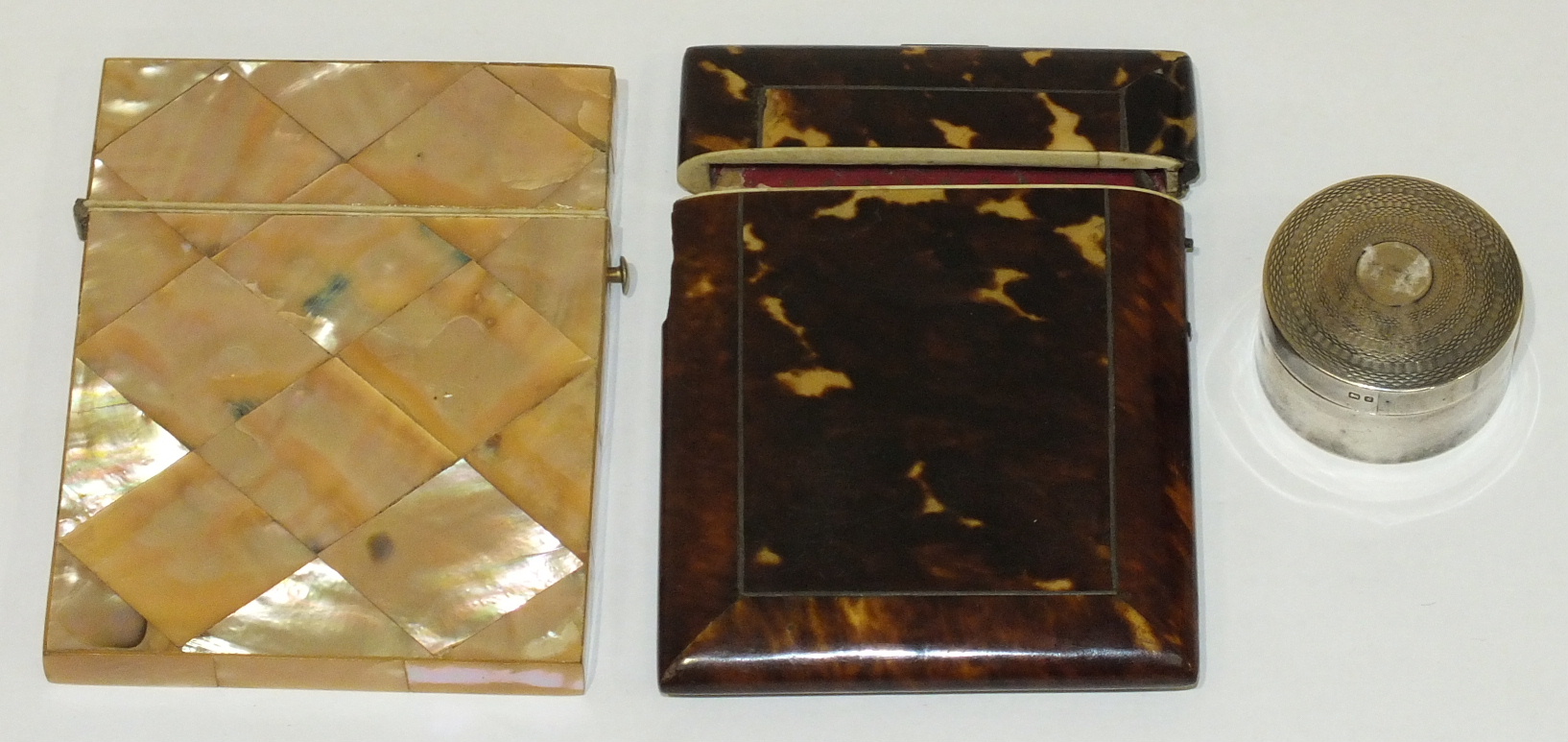 A mother-of-pearl card case, (a/f), a tortoiseshell card case, (a/f) and a circular silver pill box,