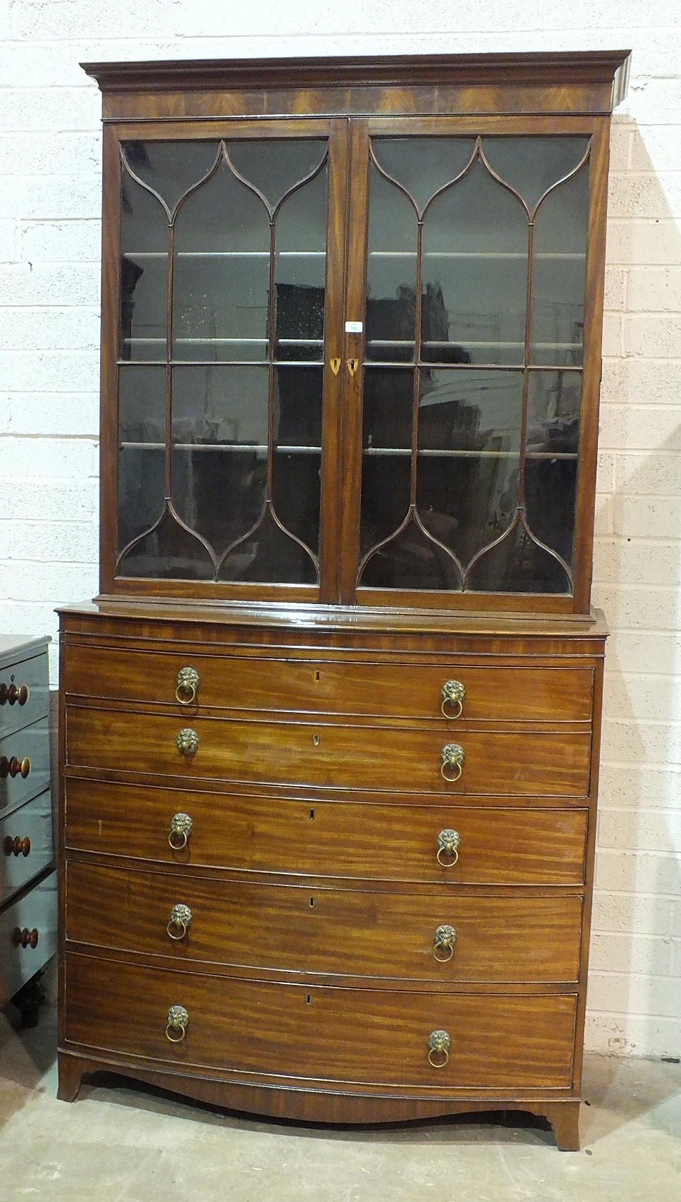 A George III mahogany bow-fronted secretaire bookcase, the moulded cornice above a pair of gothic