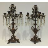 A pair of early-20th century copper finish metal five-light candelabra adorned with cut glass drops,