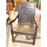 An antique oak armchair, the carved panel back and solid seat on turned legs with stretchers.