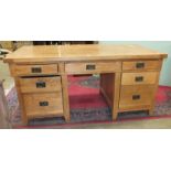 A large oak knee-hole desk, the planked top above seven drawers, 180cm wide, 86cm deep, 84cm high.