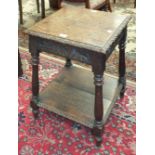 An early-20th century oak two-tier occasional table with carved borders and splayed turned legs,