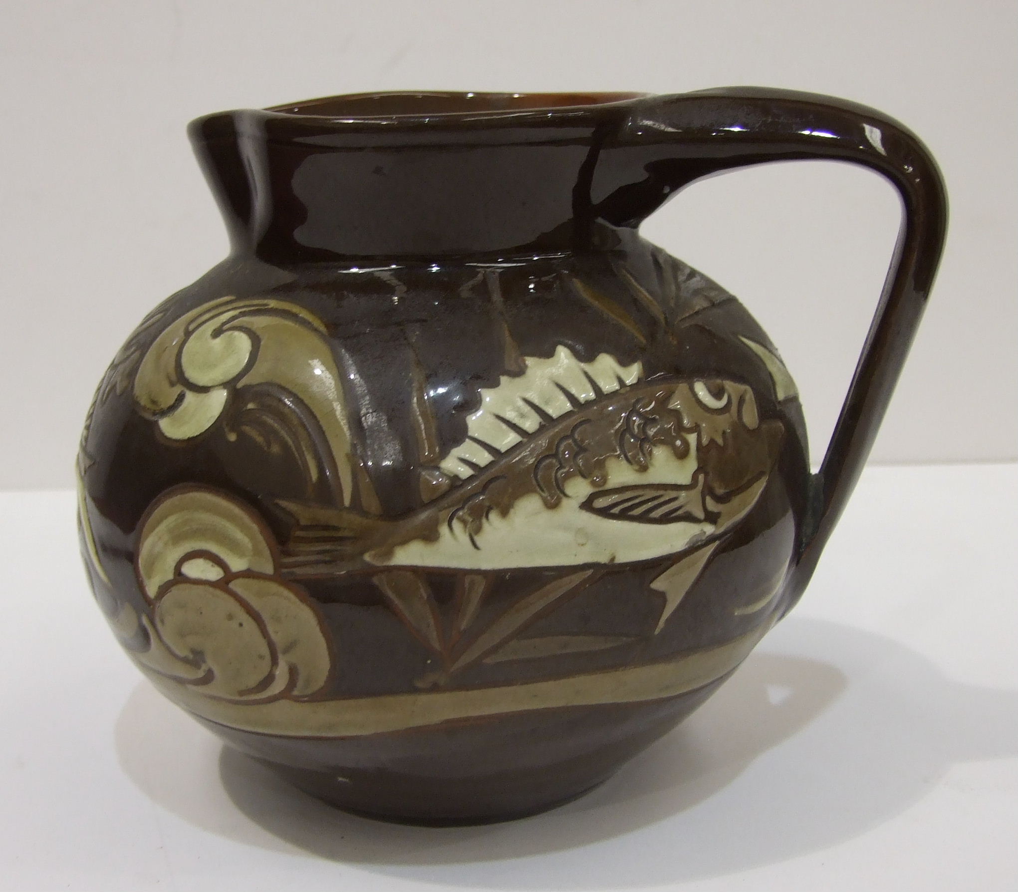 C H Brannam, Barum, a brown-glazed jug of compressed form, with incised marks beneath, dated 1892.