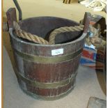 A brass coopered teak bucket with rope carrying handle, 33cm high, 31cm diameter.