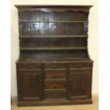 A stained pine dresser, the open shelved top above three frieze drawers, three central doors flanked