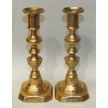 A pair of 19th/20th century brass candlesticks with candle ejector mechanisms and numbered