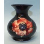 A small Moorcroft baluster vase decorated with anemones, on a dark blue ground, marked 'Moorcroft,