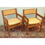 A set of four Scandinavian hardwood dining chairs with raffia backs and seats, two with arms, a