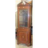 An Edwardian cross-banded and inlaid mahogany corner cupboard fitted with a glazed door above a