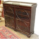 A 20th century mahogany floor-standing display cabinet with carved gallery top above a pair of