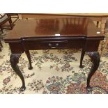 A mahogany fold-over card table in the George II style, the top with recess counter dishes above a