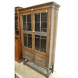 An oak-glazed bookcase with carved detail, 106cm wide, 183cm high.