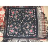 A Chinese black silk shawl, embroidered overall with flowers in coloured silks, with deep