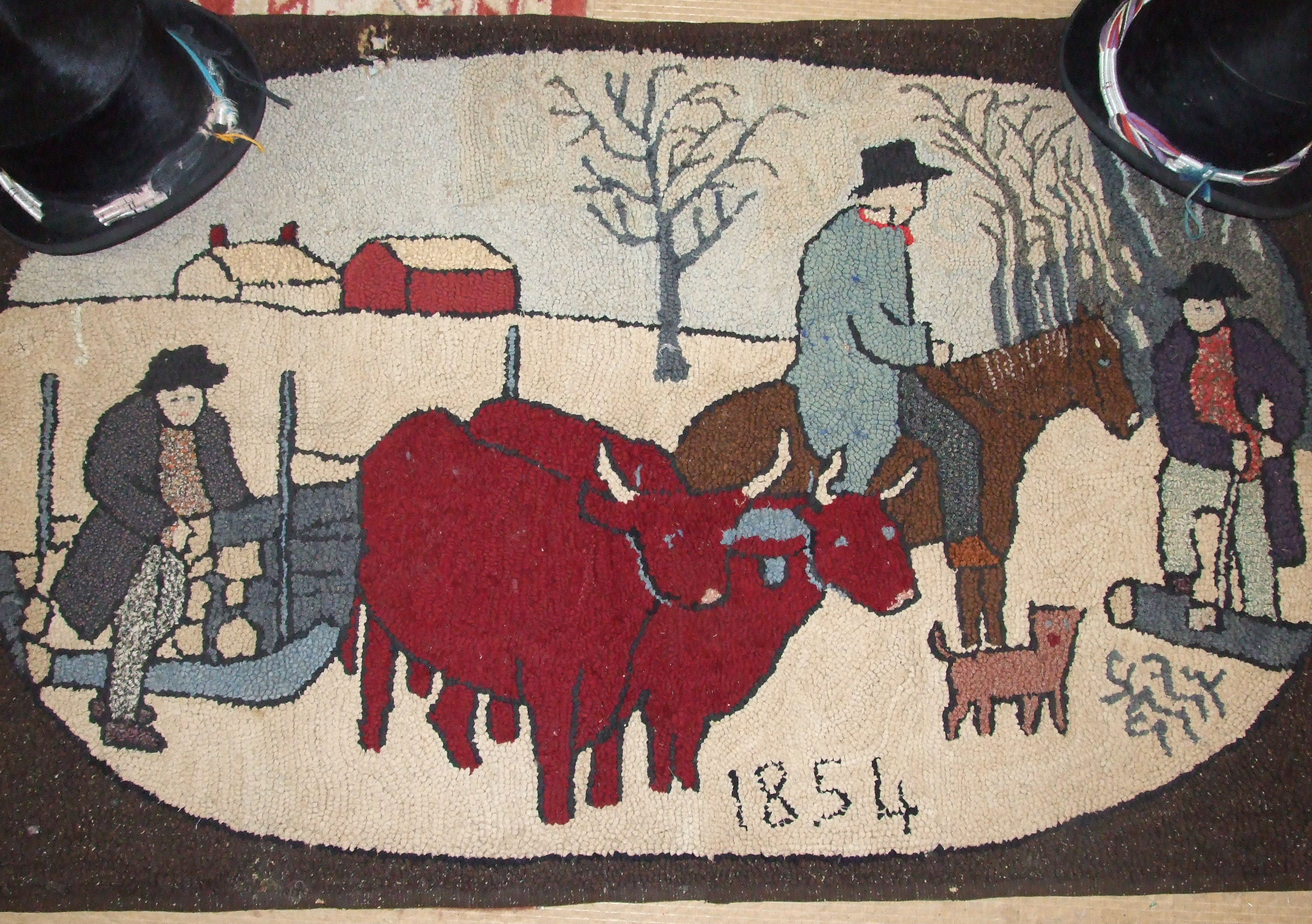 A rag rug depicting oxen and figures in a snowy landscape and dated 1854, and two top hats.