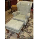 A Georgian-style upholstered wing armchair on claw and ball feet and a similarly-upholstered foot
