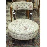 A Victorian walnut nursing chair with circular padded seat and back rail.