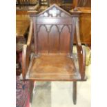 A 19th century oak armchair with Gothic-style back and solid seat, on X-shaped legs, a similar chair