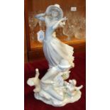 A Lladro figure of a young woman holding on to her bonnet in a breeze, 35cm high and a Nao figure of