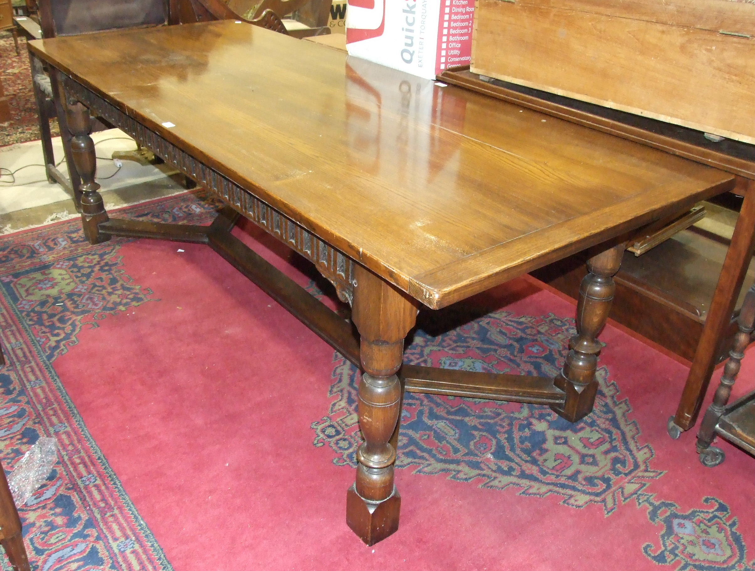 A reproduction oak plank-top dining table on bullet-moulded frieze and turned legs joined by