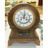 An oak-cased arched-top striking mantel clock with visible escapement, 38cm high and a stained