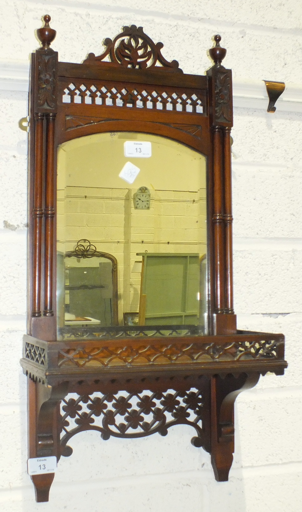 A late-19th/early-20th century walnut-framed hall mirror fitted with a shelf and pierced decoration,