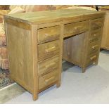 A modern solid light oak knee-hole desk with three frieze drawers and six pedestal drawers with wood