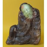 A Chinese stone figure with carved jade face and hand, 12.5cm high.