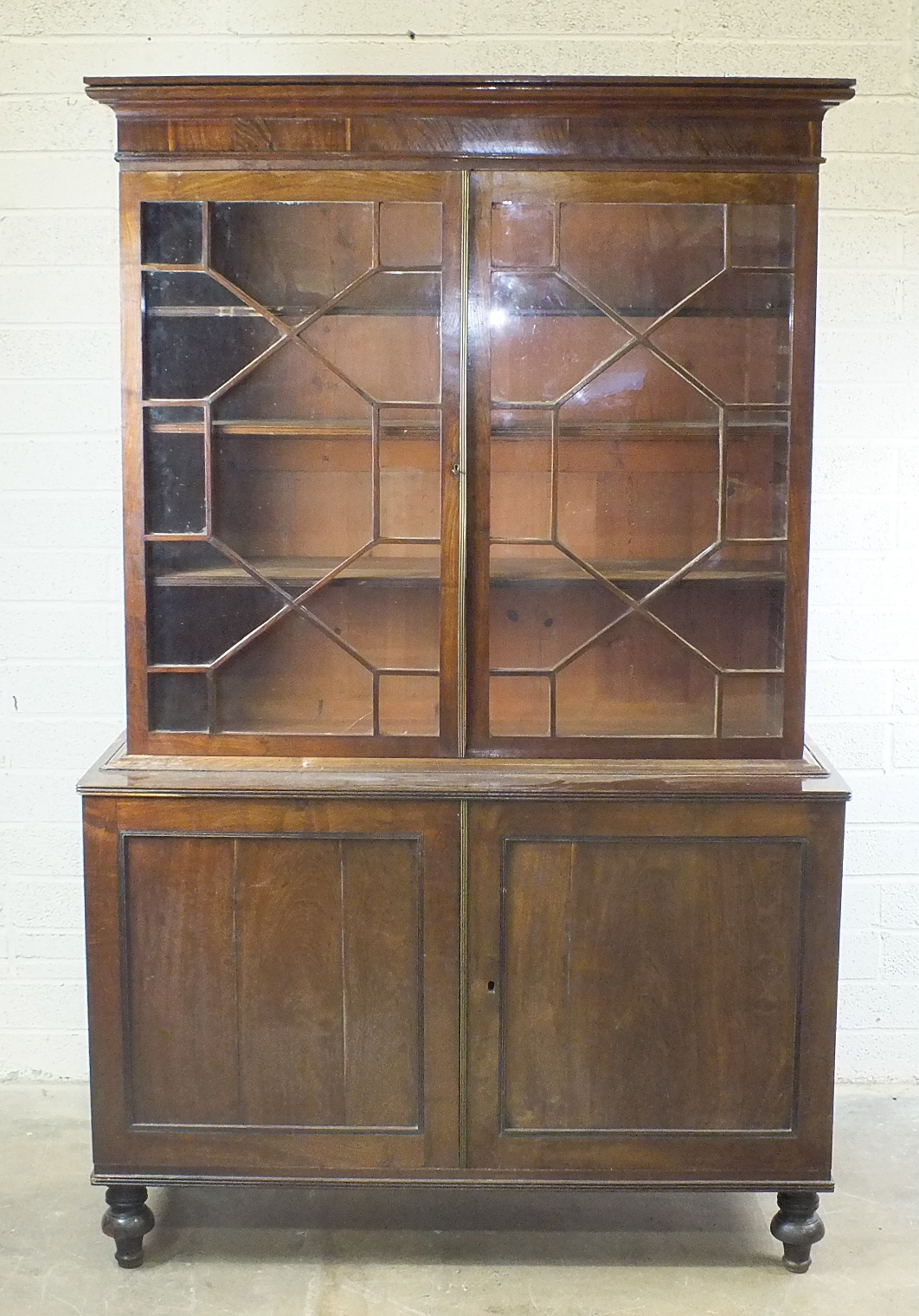 A Colonial hardwood bookcase, the cornice above a pair of astragal glazed doors and a pair of