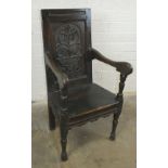 An antique oak hall chair, the carved panelled back, solid seat and arms raised on turned front