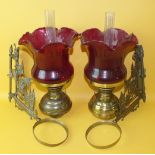 A pair of Edwardian brass bracket-mounted oil lamps with ruby glass shades, (2).