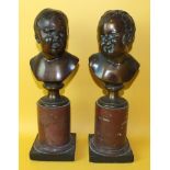 A pair of bronze busts of infants' heads, one smiling, the other crying, on marble plinths, 30cm