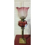 A Late-Victorian oil lamp, the cranberry glass reservoir on brass Corinthian column.