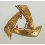 An 18ct gold brooch of open triangular form set three round cut rubies, 4cm, 5.5g.