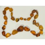 A necklace of graduated irregularly shaped amber beads with white metal links, 63.5g.